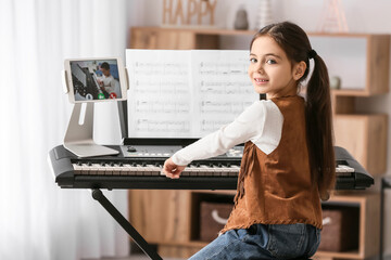 Little girl studying music with her friend online at home