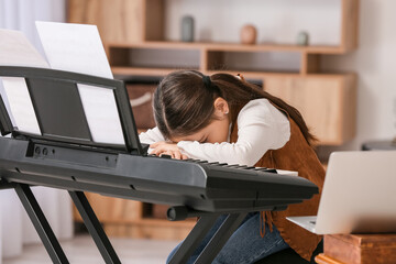 Bored little girl taking music lessons online at home