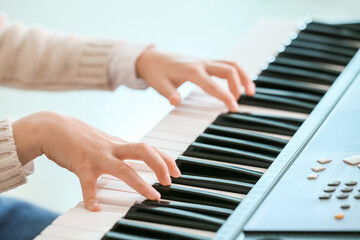 Little girl playing synthesizer at home, closeup