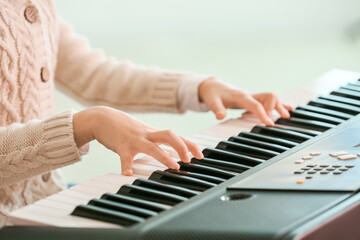 Little girl playing synthesizer at home, closeup
