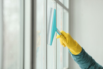 Young man cleaning window at home