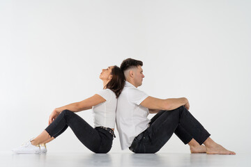 Pensive man and woman sitting back to back after quarrel on white background. copy space 