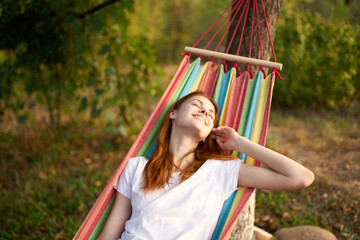 happy woman lies in a hammock outdoors in the forest laughing smile model