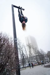 Foto op Aluminium Young attractive Girl hanging by feet upside down on the street light in the street. super extreem. concept of courage and meditation © Hladchenko Viktor