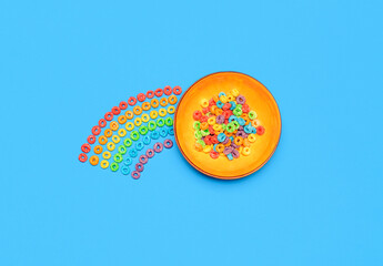 Cereal bowl isolated on blue background. Rainbow fruit-flavored ring cereals, top view