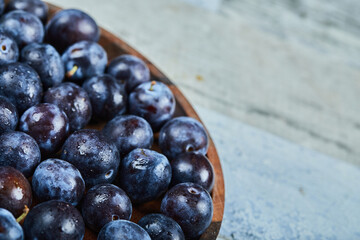 Garden plums in a plate on a blue background