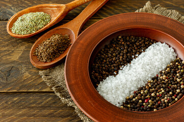 Assorted spices in a plate, spoons and bowls on wooden background