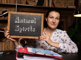 Business woman holding chalkboard with written text Animal Spirits - closeup shot.