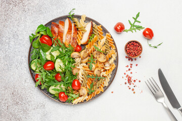 Grilled chicken breast, pasta fusilli, arugula, tomatoes, mushrooms and fresh lamb salad in plate. Top view