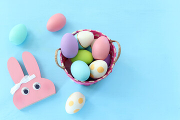 Cute bunny next to easter colorful eggs over pastel background