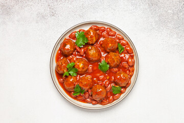 Meat or vegetable meatballs in tomato sauce with beans. Top view.