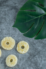 Obraz na płótnie Canvas Dried pineapples with green leaves on a gray background