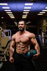 Fototapeta na wymiar happy smiling strong young bearded athlete with medicine heavy ball in blue lit night sport gym