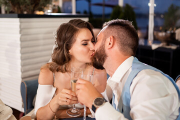 newlyweds kiss and hug in restaurant and listen to congratulations from guests.