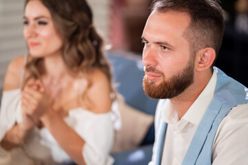 newlyweds sit at table in restaurant and listen to congratulations from guests.