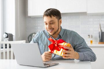 A man with a giftbox during an online video call. Onilne dating concept.