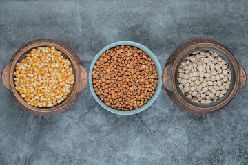 Different kinds of uncooked beans and corns in various pots