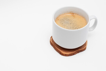 White cup with fresh black americano coffe on circle wooden cut.