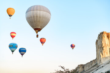 Fototapeta premium Colorful air balloons flying in clear sky near huge white mountain