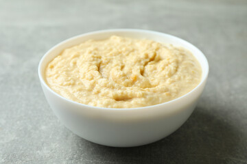 Bowl of fresh hummus on gray background