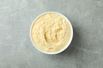 Bowl of fresh hummus on gray background