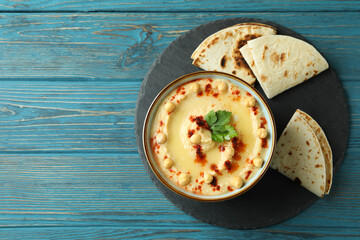 Tray with bowl of hummus and pita on wooden background