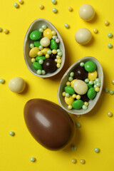 Easter chocolate eggs and candies on yellow background