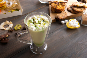 A mug of marshmallow drink on the table by the window.