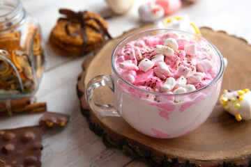A mug of marshmallow drink on the table by the window.