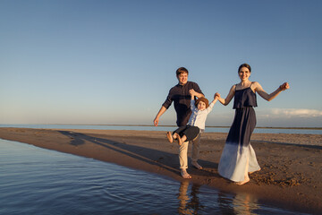 Fototapeta premium Young family with child have fun on the beach. Copy space.