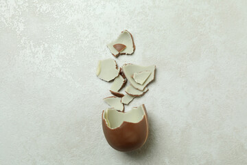 Broken chocolate egg on white textured background