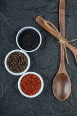 Wooden spoons with spices on a dark background