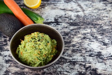 Fresh Tasty Vegetable Vegetarian or Vegan Grated Salad with Carrot Zucchini Sesame and Avocado Sauce in A Bowl