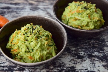 Fresh Tasty Vegetable Vegetarian or Vegan Grated Salad with Carrot Zucchini Sesame and Avocado Sauce in A Bowl