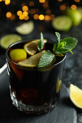 Glass of Cuba Libre cocktail against blurred lights, close up