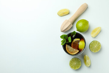Glass of Cuba Libre, limes and wooden juicer on white background, top view