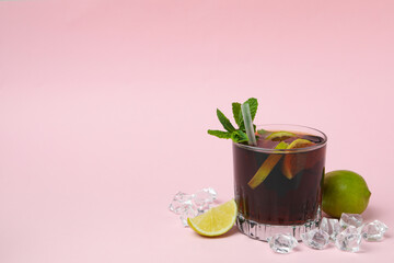 Glass of Cuba Libre cocktail on pink background