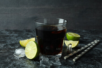 Glass of Cuba Libre and ingredients on black smokey table