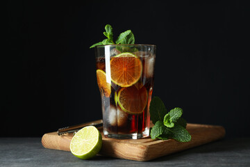 Board with glass of Cuba Libre against dark background