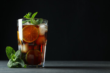 Glass of Cuba Libre and mint against dark background