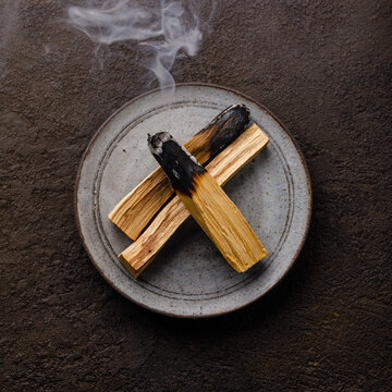 Smoking organic herbal Incense Palo santo stick on dark background