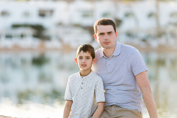 Man and boy are sitting on the beach of the lake. Father and son. Father's day. Family vacation. Holiday