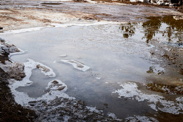 Ice and snow in puddles in spring or autumn time. Thaw after winter in nature landscape