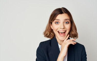 Energetic business woman in a suit gestures with her hands on a light background Copy Space