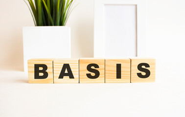 Wooden cubes with letters on a white table. The word is BASIS. White background.