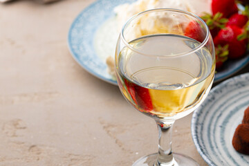 Glass of white wine, truffel chocolates and strawberry close up