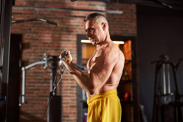 Sporty man cringing a bit while pulling weights