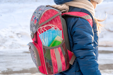 Pink backpack with hand sanitizer (hand rub) and medical face shield. The briefcase is not on the child's back. Back to school. Prevention of viruses and diseases in children.