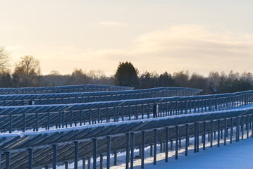 Solar panel back side field covered with snow. renewable energy in winter low efficiency. renewable green energy industry concept in winter time.