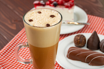 Cup of coffee and saucer with chocolate sweets on wooden table
